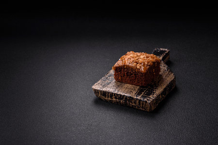 Chocolate sweet brownie cake in a square shape on a dark texture background