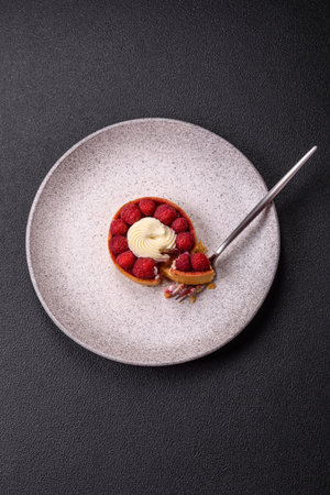 Sweet tartlet with raspberries and cream on a dark textured background