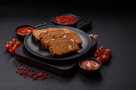 Brown bread with seeds, grains, salt and spices on a dark concrete backgroundの写真素材
