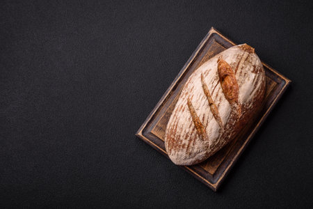 Brown bread with seeds, grains, salt and spices on a dark concrete backgroundの写真素材