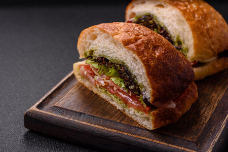 Ciabata with jamon or prosciutto, tomatoes, cheese and lettuce with salt, spices and herbsの写真素材