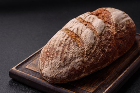 Brown bread with seeds, grains, salt and spices on a dark concrete backgroundの写真素材