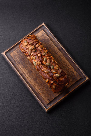 Brown bread with seeds, grains, salt and spices on a dark concrete backgroundの写真素材