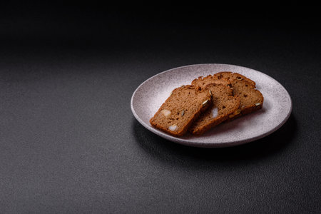Brown bread with seeds, grains, salt and spices on a dark concrete backgroundの写真素材