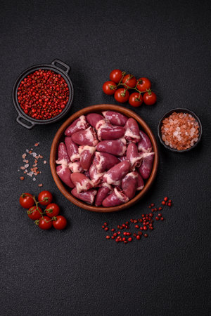 Raw chicken hearts with salt, spices and herbs on a dark concrete backgroundの写真素材