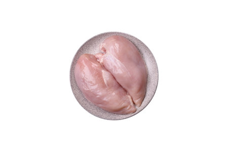 Pieces of raw chicken fillet with salt, spices and herbs on a white backgroundの写真素材