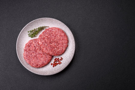 Fresh raw ground beef burger patty with salt and spices on textured concrete backgroundの写真素材