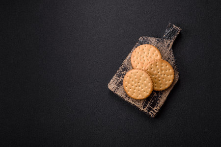 Round dotted snack snack cookies with cream on a dark concrete background. Sweets for breakfastの写真素材