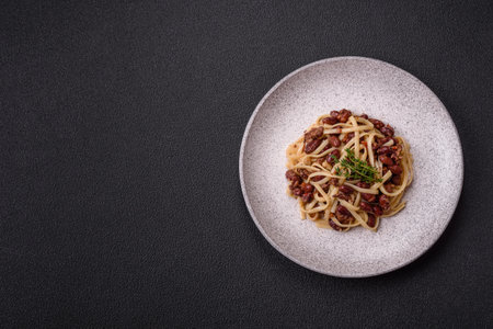 Noodles with beans, meat, tomato sauce, spices and herbs on a dark concrete backgroundの写真素材