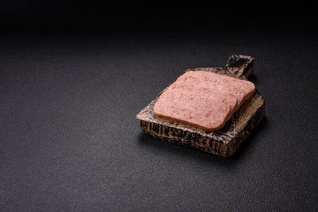 Delicious canned pink spiced ham with salt, spices and herbs on a dark backgroundの写真素材