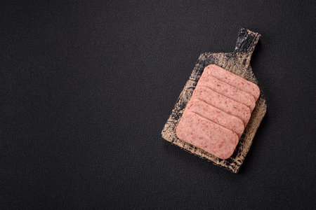 Delicious canned pink spiced ham with salt, spices and herbs on a dark backgroundの写真素材