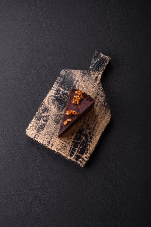 Piece of sweet chocolate cake with nuts on dark concrete backgroundの写真素材