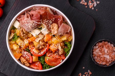 Appetizing salad with prosciutto, baked pumpkin, cheese, lettuce, tomatoes and sesame seedsの写真素材