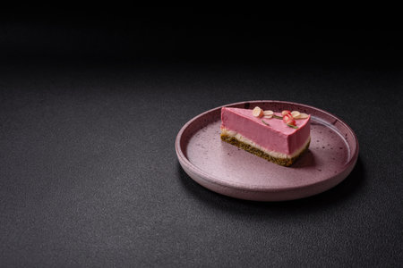 Piece of sweet cheesecake with pink cream cheese of raspberry or strawberry flavor on a dark...