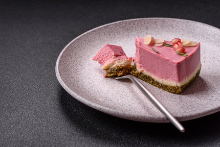Piece of sweet cheesecake with pink cream cheese of raspberry or strawberry flavor on a dark textured backgroundの写真素材
