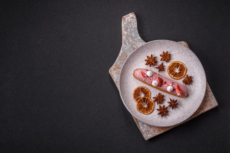 Sweet eclair or profiterole with strawberry custard on a dark textured backgroundの写真素材