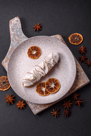 Sweet eclair with custard decorated with coconut slices on a dark concrete backgroundの写真素材