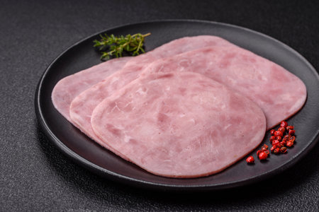 Ham with salt, spices and herbs cut into slices on a dark concrete background
