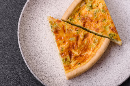 Delicious quiche with broccoli, chicken or salmon and cheese with salt and spices on a dark concrete...