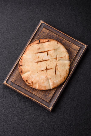 Round flatbread or pita with cheese, herbs, salt and spices, baked on the grill