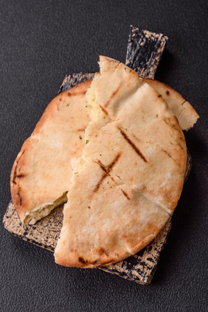 Round flatbread or pita with cheese, herbs, salt and spices, baked on the grill