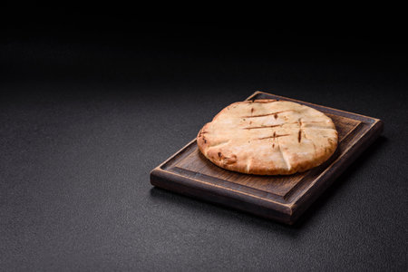 Round flatbread or pita with cheese, herbs, salt and spices, baked on the grill