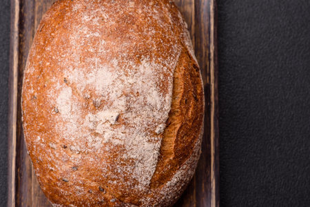 Brown bread with seeds and grains for sandwiches on a dark concrete background
