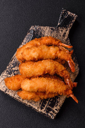 Hot crispy shrimp breaded with salt and spices with white sauce on a dark concrete backgroundの写真素材