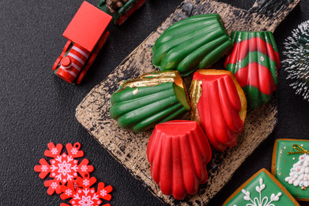 Sweet Madeleines desserts covered with chocolate in Christmas colors, with various toppings on a dark concrete backgroundの写真素材