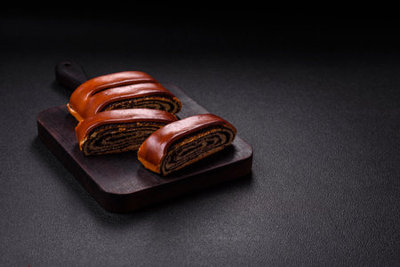 Sweet homemade roll with poppy seeds on a dark concrete backgroundの写真素材