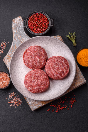 Fresh raw ground beef burger patty with salt and spices on textured concrete backgroundの写真素材