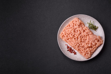 Raw minced chicken with salt, spices and herbs on a dark concrete backgroundの写真素材