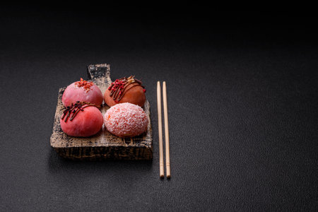 Delicious colorful asian mochi sweets with rice dough shell and fruit filling on dark concrete...