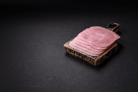Boiled ham cut into square slices on a dark concrete backgroundの写真素材