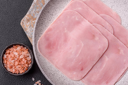 Boiled ham cut into square slices with sorrel and spices on a dark concrete background