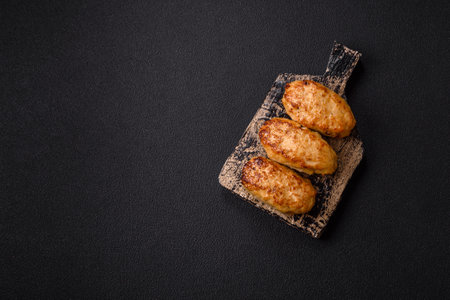 Delicious fresh fried minced fish cutlets with spices and herbs on a dark concrete backgroundの写真素材
