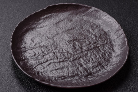 Empty black ceramic plate on a dark concrete background. Preparing the table for a family dinnerの写真素材