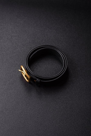 New leather belt with an old-style metal buckle on a dark concrete backgroundの写真素材