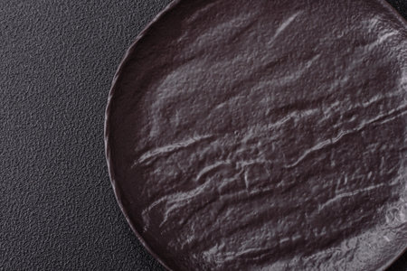 Empty black ceramic plate on a dark concrete background. Preparing the table for a family dinnerの写真素材