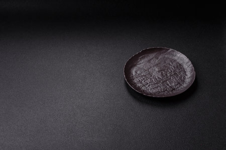 Empty black ceramic plate on a dark background.の写真素材