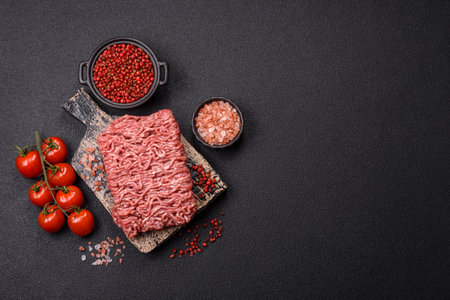 Fresh raw ground minced beef with salt and spices on textured concrete backgroundの写真素材