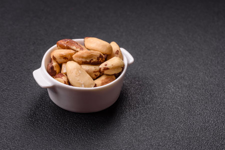 Delicious nutritious brazil nuts in ceramic bowl on dark concrete backgroundの写真素材