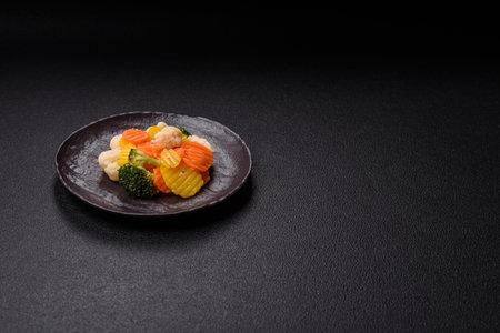 Fresh vegetables steamed carrots, broccoli, cauliflower on a black plate on a dark backgroundの写真素材