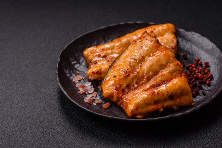 Grilled fish fillet with salt, spices and herbs on dark concrete background