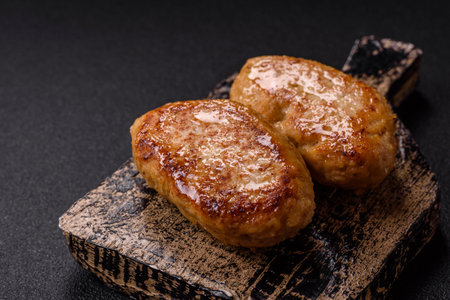 Delicious fresh fried minced fish cutlets with spices and herbs on a dark concrete background
