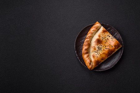 Cheburek meat pastry pie with herbs. Black concrete background. Top view