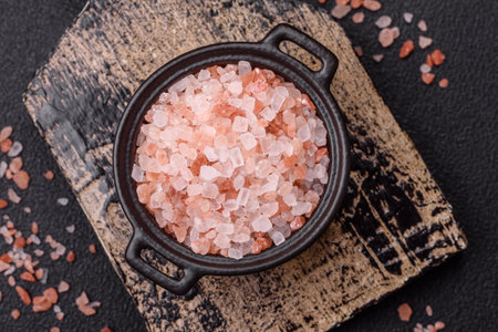 Pink himalayan salt in a black bowl on a dark concrete background. Seasonings and additives in the kitchenの写真素材