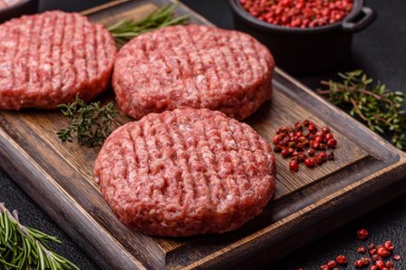 Fresh raw ground beef burger patty with salt and spices on textured concrete backgroundの写真素材