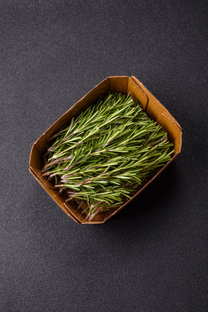 Fresh green rosemary sprigs prepared for cooking, on dark concrete backgroundの写真素材