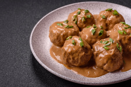 Meatballs with salt and spices in creamy caramel sauce on a dark concrete background